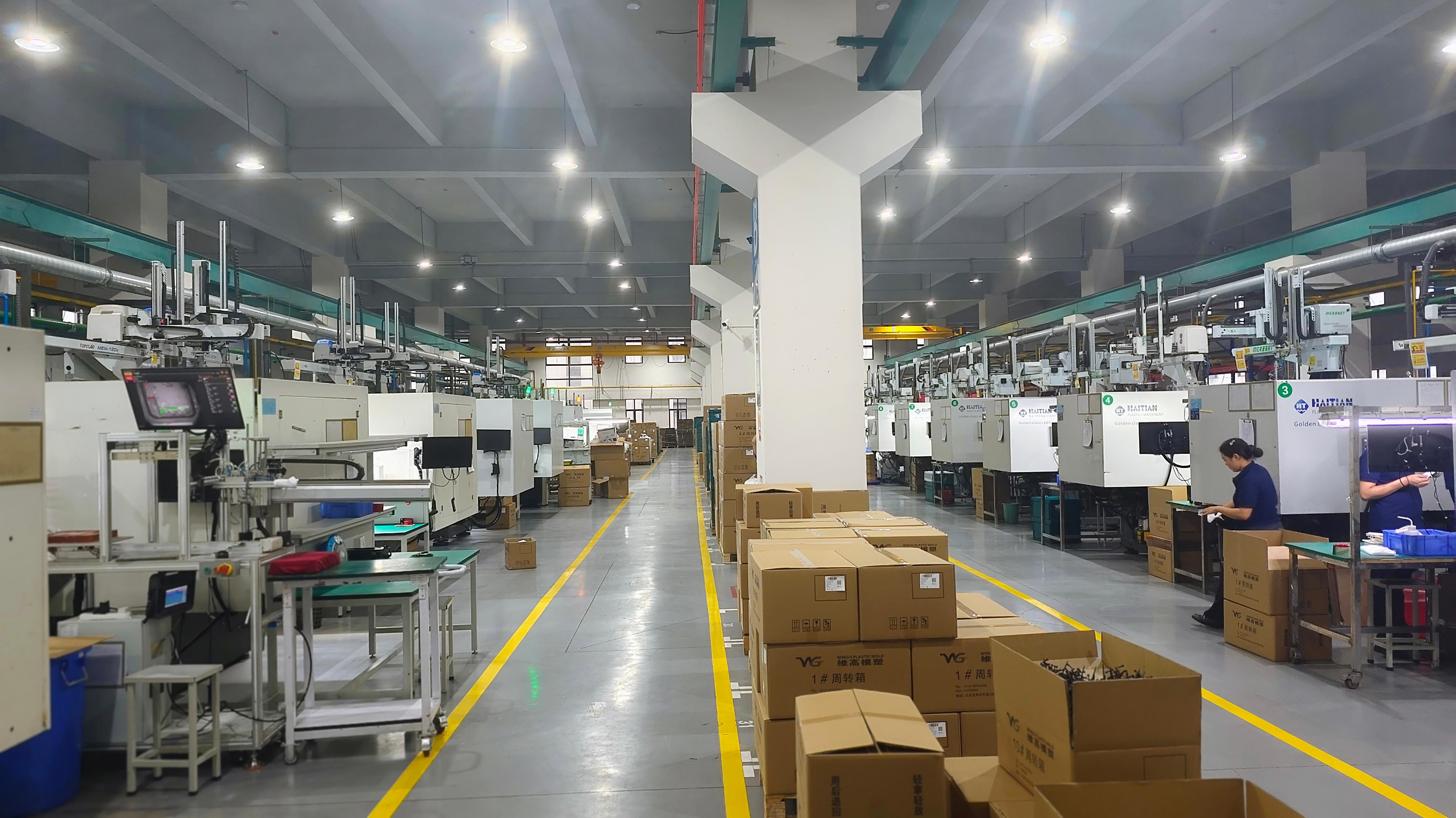 Wide view of the automated injection molding workshop with machines on both sides of the central aisle