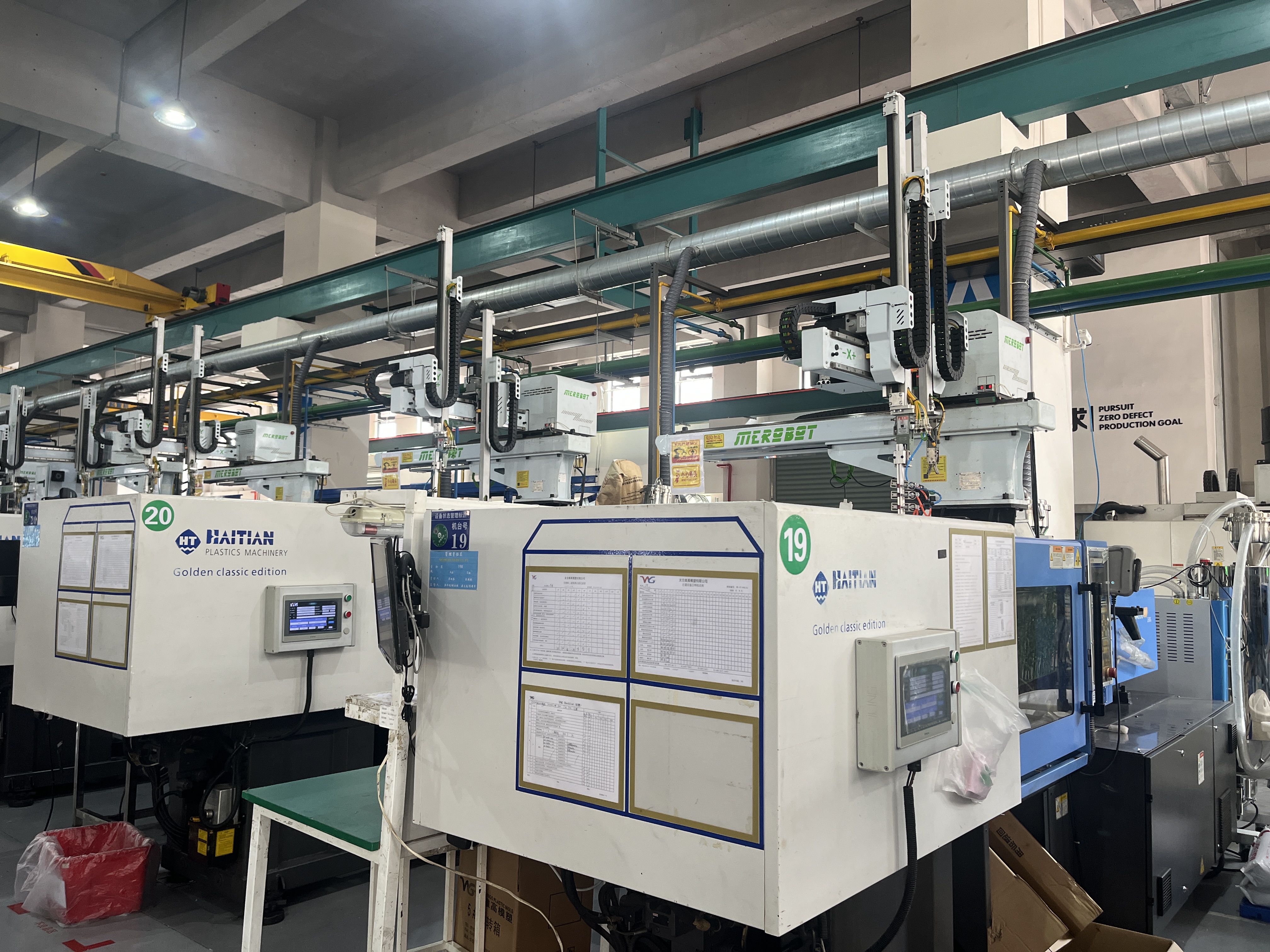 Automated injection molding production line with a robotic arm handling molded parts beside rows of finished housings