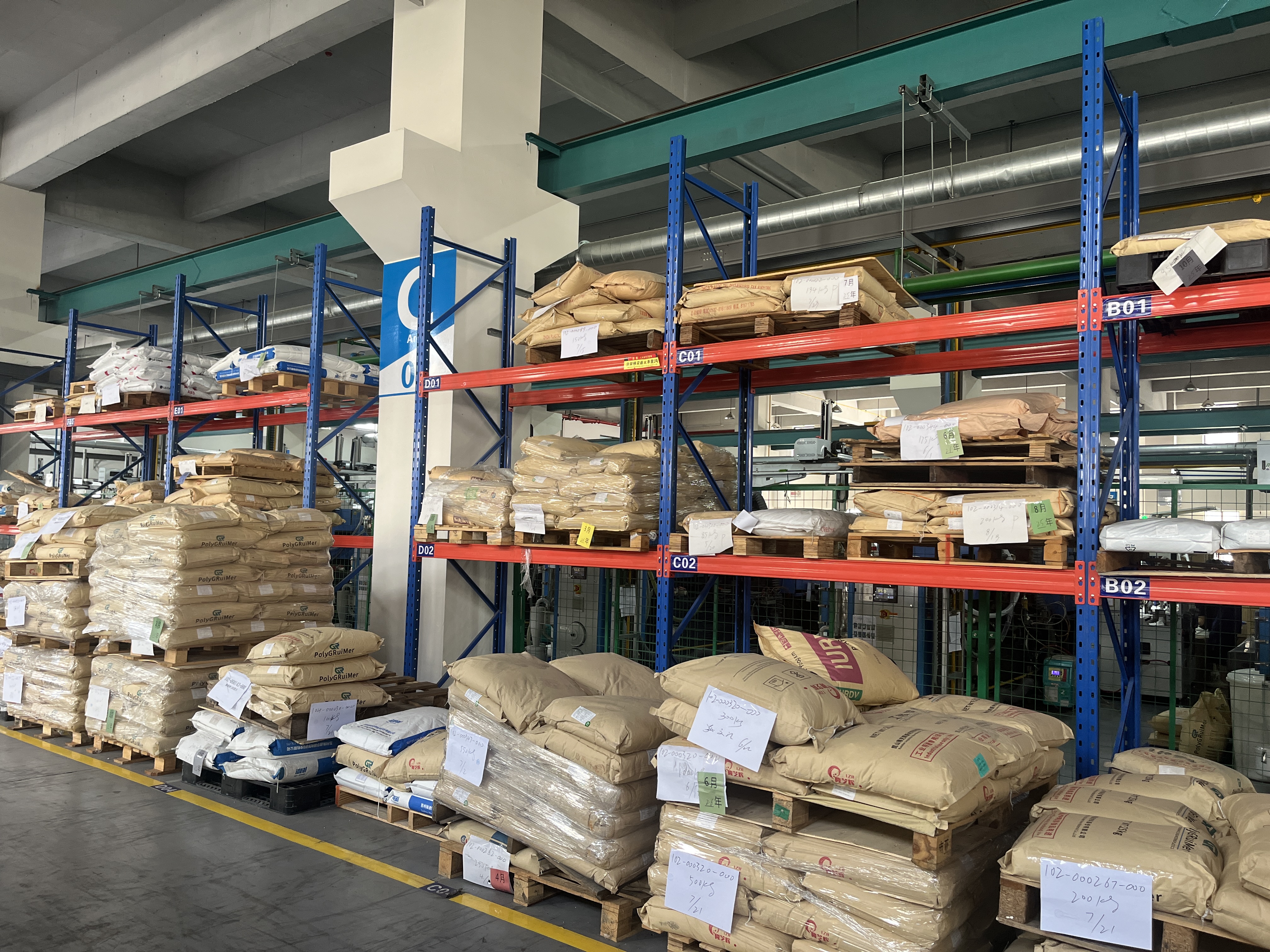 Raw material warehouse with labeled resin pallets on industrial racking
