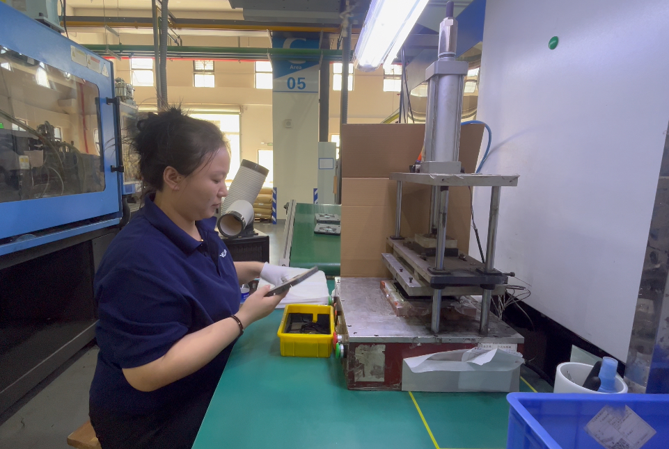 Wingo Plastic quality operator inspecting molded parts beside the production line